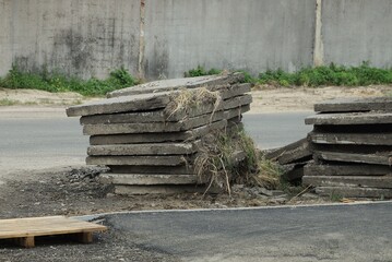 pile of old square concrete slabs on a repaired asphalt road in the street