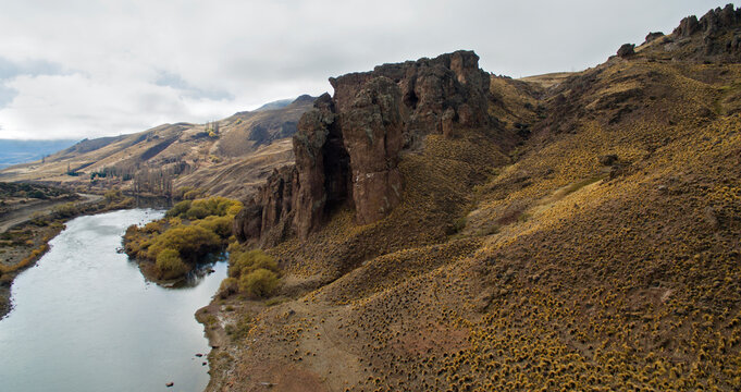 Rural landscape. Aerial view of the river flowing across the valley, mountains, rocky formations and  golden meadow in autumn. 