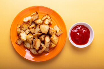 fried potatoes on orange plate and ketchup