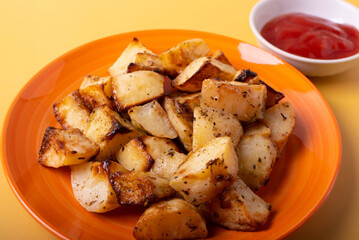 fried potatoes on orange plate and ketchup