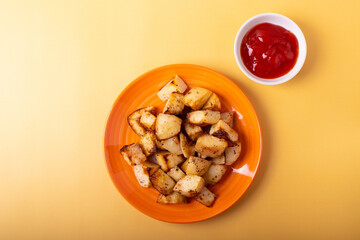 fried potatoes on orange plate and ketchup