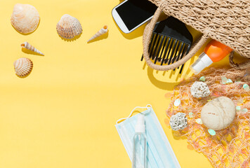 Beach objects, face mask and hydro alcoholic gel on yellow background.