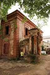 Young curious tourist boy explore the old abandoned ruined red brick house in the old russian outback town Ostashkov