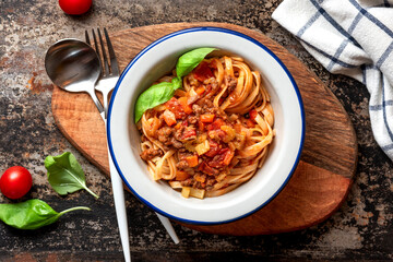 Pasta Bolognese. Tagliatelle with homemade bolognese sauce of minced meat, tomatoes, celery, carrots and spices in a bowl on a black background, top view. Italian Cuisine. 