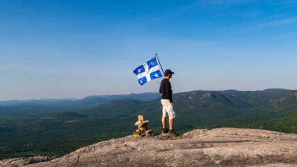 Man with a fleurdelisé flag from Quebec on the top of "La Chouenne" mountain in Charlevoix