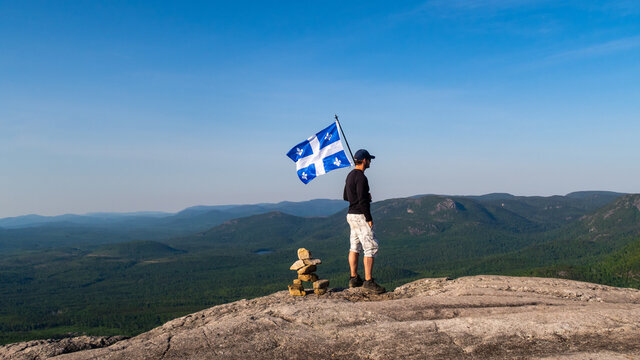 Man with a fleurdelis&eacute; flag from Quebec on the top of "La Chouenne" mountain in Charlevoix