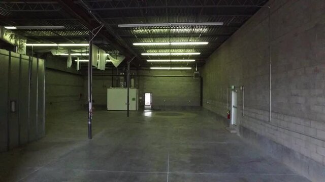 Aerial video of empty warehouse. This video shows warehouse with ceiling lights and walls.