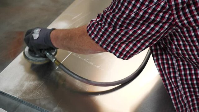 Slow motion video of a man using polishing tool. High Angle Shot Of A Male Hand Buffing A Metal Sheet.