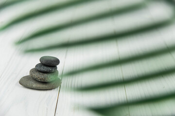 Pyramids of gray zen pebble meditation stones with green leaves on white wooden background. Concept...