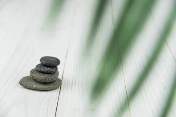 Pyramids of gray zen pebble meditation stones with green leaves on white wooden background. Concept...