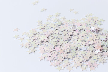 Close up. Beautiful light confetti in a form stars on a white background. Background for holidays, beauty, celebration.