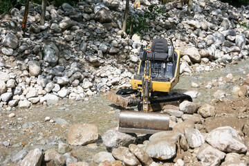Excavator in the mountan stream river.