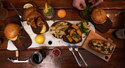 Dinner table with baked potatoes,burgers, sauces, beer and wine