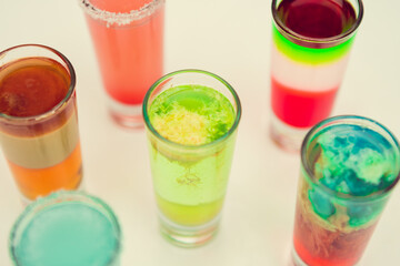 Colorful toned alcoholic shots in white background. Several alcohol shots on sunny bar.