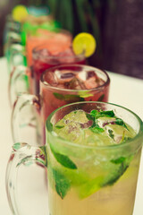 Colorful toned cocktails in big glasses on white background. Vertical shot.
