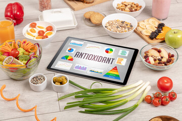 Organic food and tablet pc showing ANTIOXIDANT inscription, healthy nutrition composition