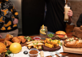 Dinner table with baked potatoes,burgers, sauces, beer and wine