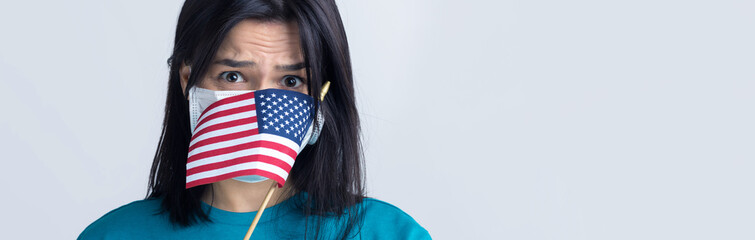 A girl in a medical mask and gloves holds an American flag in her hands. Coronavirus concept. Protect your health. .Stop the threat of a pandemic.