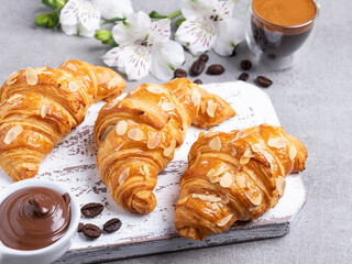 Yummy freshly three croissants, sliced almonds with coffee and chocolate paste