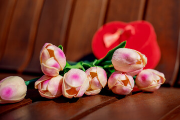 Heart shape box and tulips on wooden bench.