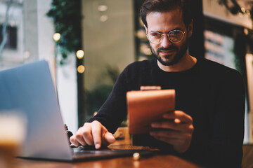 Caucasian male freelancer accounting and reading financial news while using digital devices and...