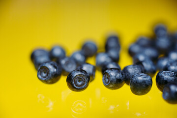 Blueberries on a yellow background top view with copy space.