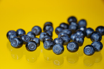 Falling blueberries or blueberries isolated on a yellow background with clipping path as a package design element and advertisement. Flying berry.