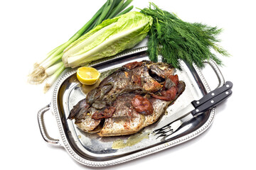 The gilt-head bream (Sparus aurata) with vegetables on a plate close-up