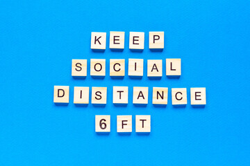 Words keep social distance 6 ft. Wooden inscription on a blue background. Information sign of keep social distance 6 ft from blocks. flat layout