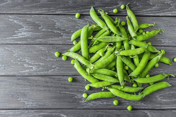 a pile of sweet green pea pods on a wooden background. green peas top view. background with fresh green peas.