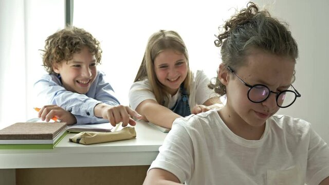 Two teens scoff at their defenseless classmate. Child cruelty. School bullying.
