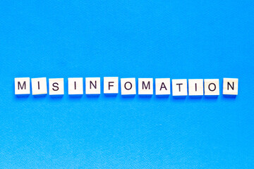 mystification written in wooden letters on a blue background, top view, flat layout, deception,...
