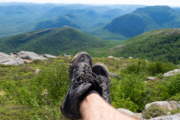 Legs of a man wearing hiking shoes at the top of the "Mont-du-lac-des-cygnes" (swan lake mountain) in Quebec