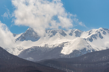 Fototapeta na wymiar Mountain with snow and puffy clouds in Italy