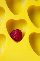 Red raspberry fruit into heart shape yellow background summer season berry dessert cooking organic food  concept