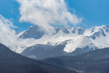 Fototapeta na wymiar Mountain with snow and puffy clouds in Italy