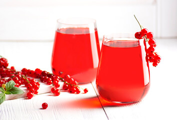Two glasses with a homemade red currant drink stand against a background of white wooden shutters, horizontal orientation, close-up.