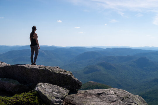 Back view of a young woman standing at the summit of the "Mont-du-lac-des-cygnes" in Charlevoix, Quebec