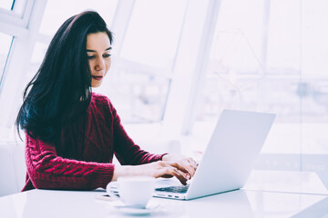 Smiling attractive copywriter browsing internet websites in searching useful information on laptop...