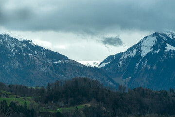 Naklejka na ściany i meble Mountain with snow and dark moody clouds in Switzerland