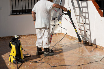 Hombre limpiando terraza con máquina de alta presión.