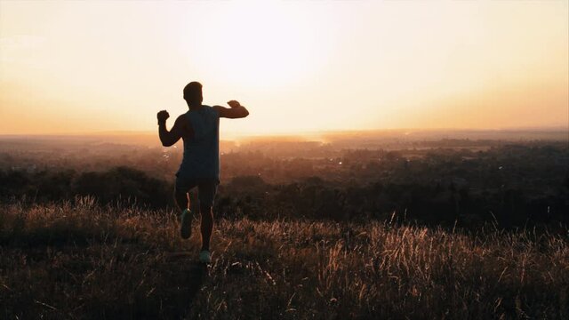 The young sportsman runs on the top of the hill with beautiful view. slow motion
