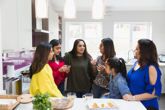 Indian women talking and cooking in kitchen