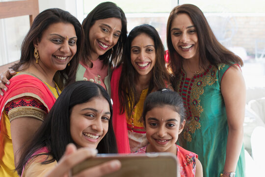 Happy Indian women and girls in saris taking selfie with smart phone
