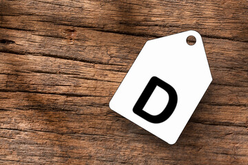 Blank label with letter D on wooden background