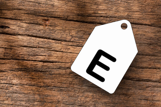 Letter E on white label on wooden background