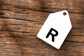 Letter R on white label on wooden background
