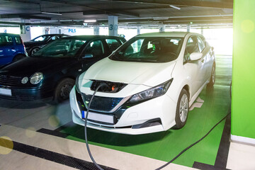 Fototapeta na wymiar Electric transports. Electric car charge battery on eco energy charger station. Hybrid vehicle - green technology of future. Eco-friendly sustainable energy concept.