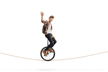 Young male student riding a unicycle on a rope and waving © Ljupco Smokovski