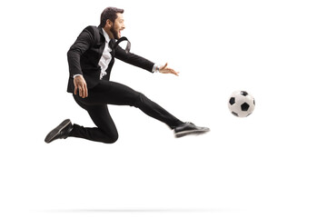 Man in a suit jumping and kicking a soccer ball